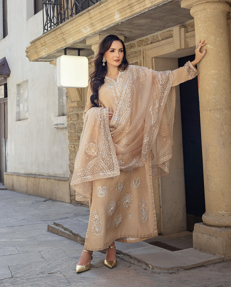 Side view of a Golden Beige Korean Raw Silk suit, hand resting against a stone pillar