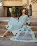 Woman reclining on stone steps wearing icy blue embroidered raw silk suit with dupatta draped