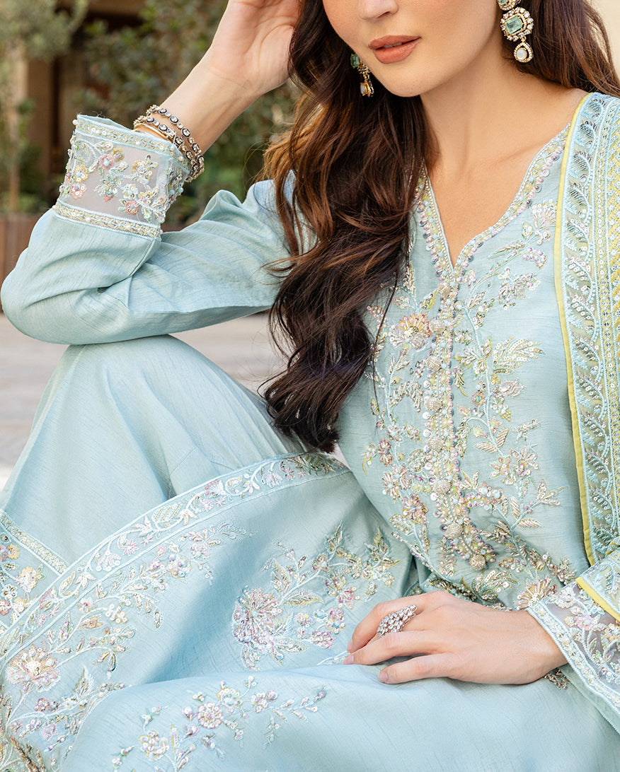 Close-up of hand-embellished sleeve cuff and neckline embroidery on icy blue raw silk shirt