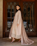 Side view of rose beige raw silk suit with organza dupatta flowing at wooden doorway
