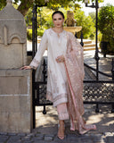Woman wearing Astrid Bloom off white embroidered raw silk suit with pink organza dupatta at garden gate