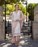 Woman wearing Astrid Bloom off white embroidered raw silk suit with pink organza dupatta at garden gate