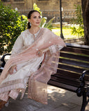 Woman wearing Astrid Bloom off white embroidered raw silk suit with pink organza dupatta at garden gate