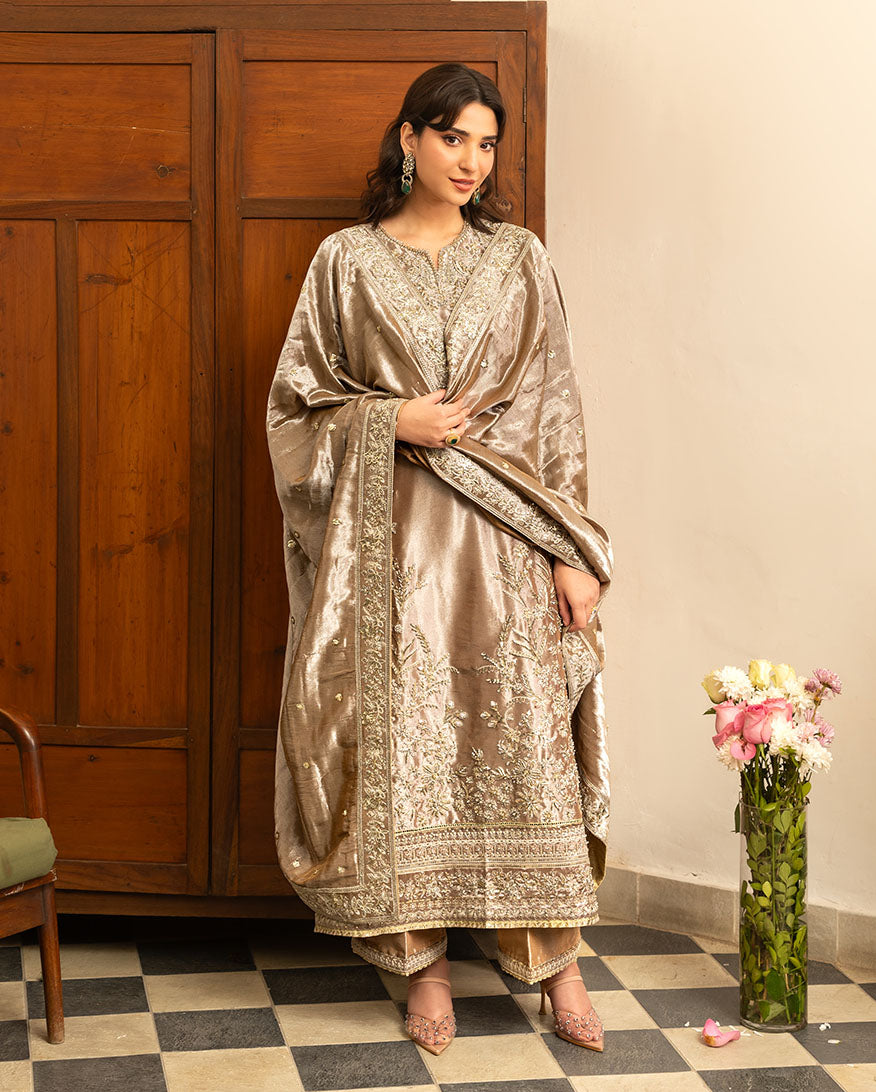 Woman wearing dark beige embellished lama silk suit, dupatta wrapped around shoulders