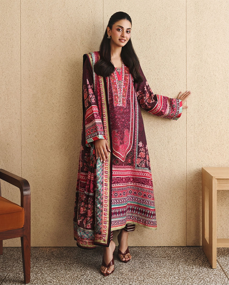 Woman wearing deep purple printed raw silk suit gesturing beside a wood-panelled wall