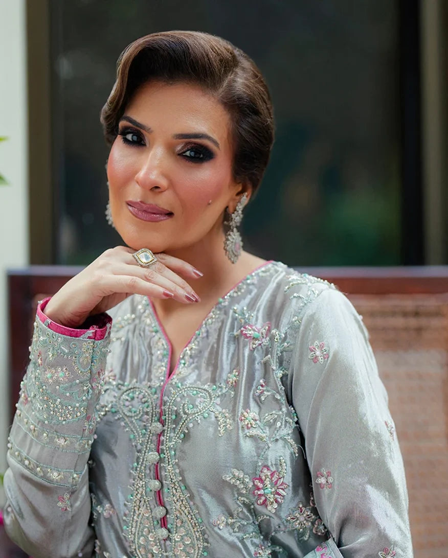 Woman wearing silver satin zari suit, close-up portrait with hand at chin