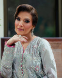 Woman wearing silver satin zari suit, close-up portrait with hand at chin