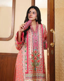 Woman wearing peach printed raw silk suit standing by a doorway, holding a clutch bag