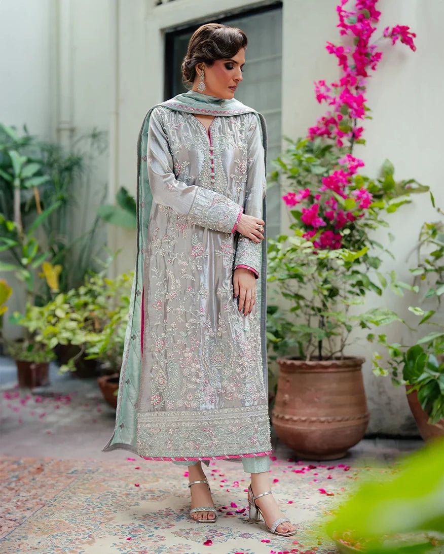 Woman wearing silver embellished satin zari suit, front standing, looking down