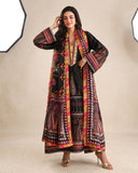 Woman wearing black printed raw silk suit with hand in hair against a studio backdrop