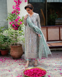 Woman wearing silver embellished satin zari suit, dupatta held to the side, rose petals on ground
