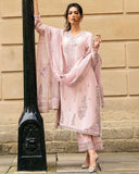 Woman in pink embroidered raw silk kurta with Swarovski crystal and tilla work, standing by stone window