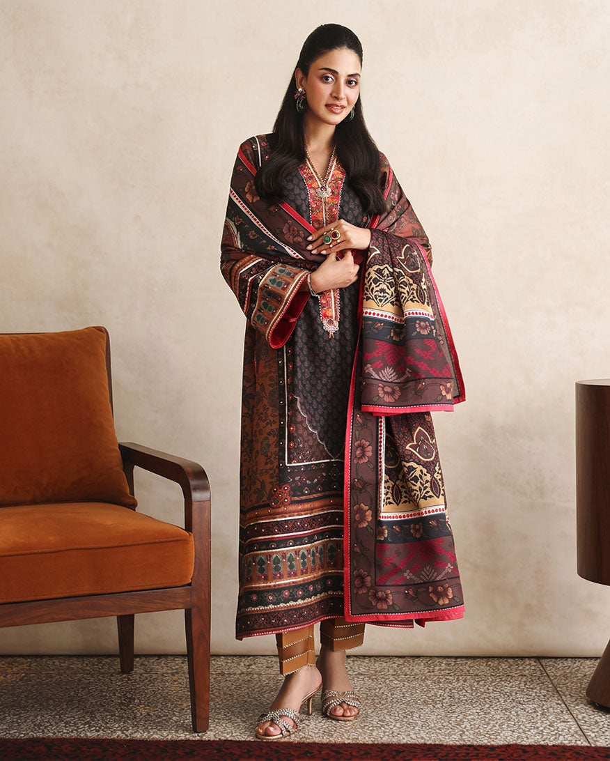 Woman wearing black printed raw silk suit standing beside a chair, holding dupatta