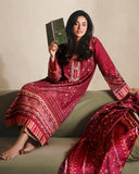 Woman wearing red printed raw silk suit seated on a sofa holding a book