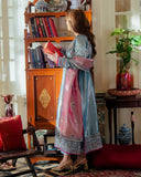 Woman wearing blue embellished satin zari suit, side standing, dupatta draped, holding a book