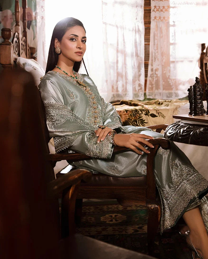 Woman wearing sea green silver zarri silk suit, seated side view in armchair