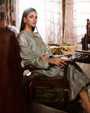Woman wearing sea green silver zarri silk suit, seated side view in armchair