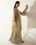 Side profile of a Pale Gold Net suit, its sheer sleeve and dupatta trailing with crystal embellishment