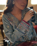 Woman wearing blue satin zari suit, close-up of embellished bodice with hand raised