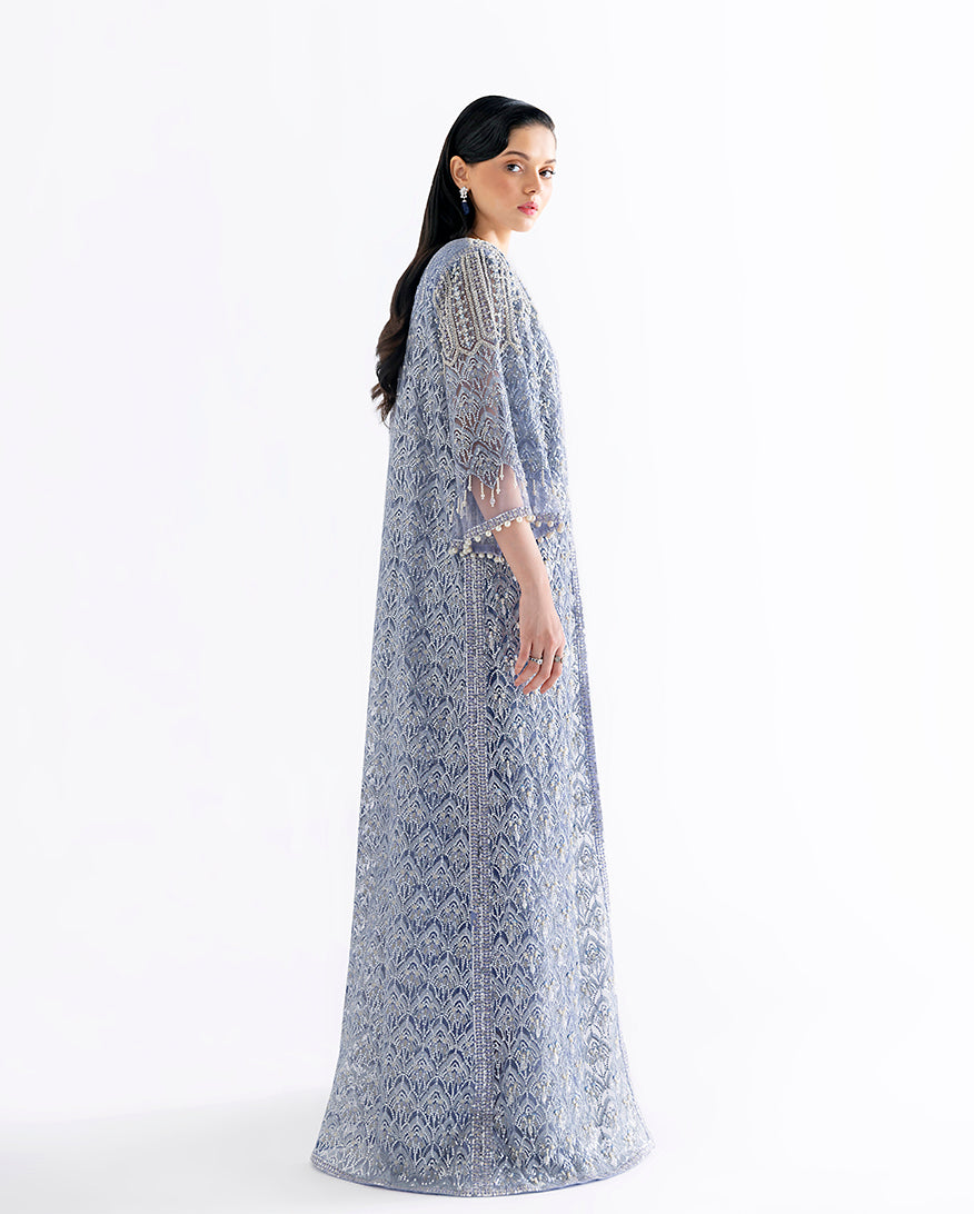 Side view of blue net suit showing fringed cape jacket draping and lattice embroidery