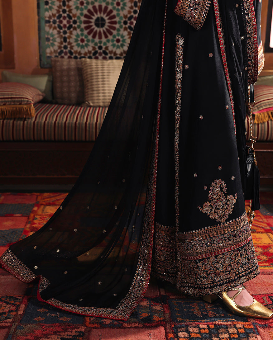 Close-up of embroidered front daman motif and sequinned hem border on black raw silk shirt