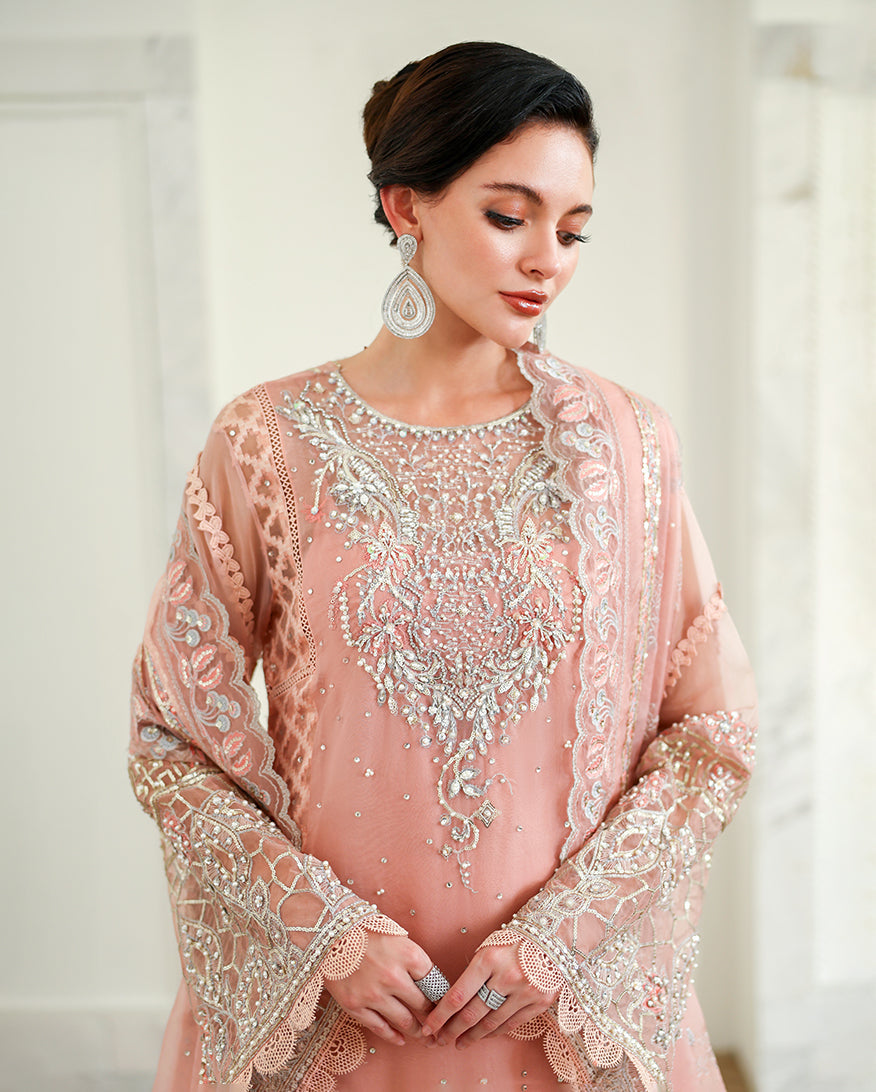 Woman wearing peach pink organza suit, close-up showing embellished neckline