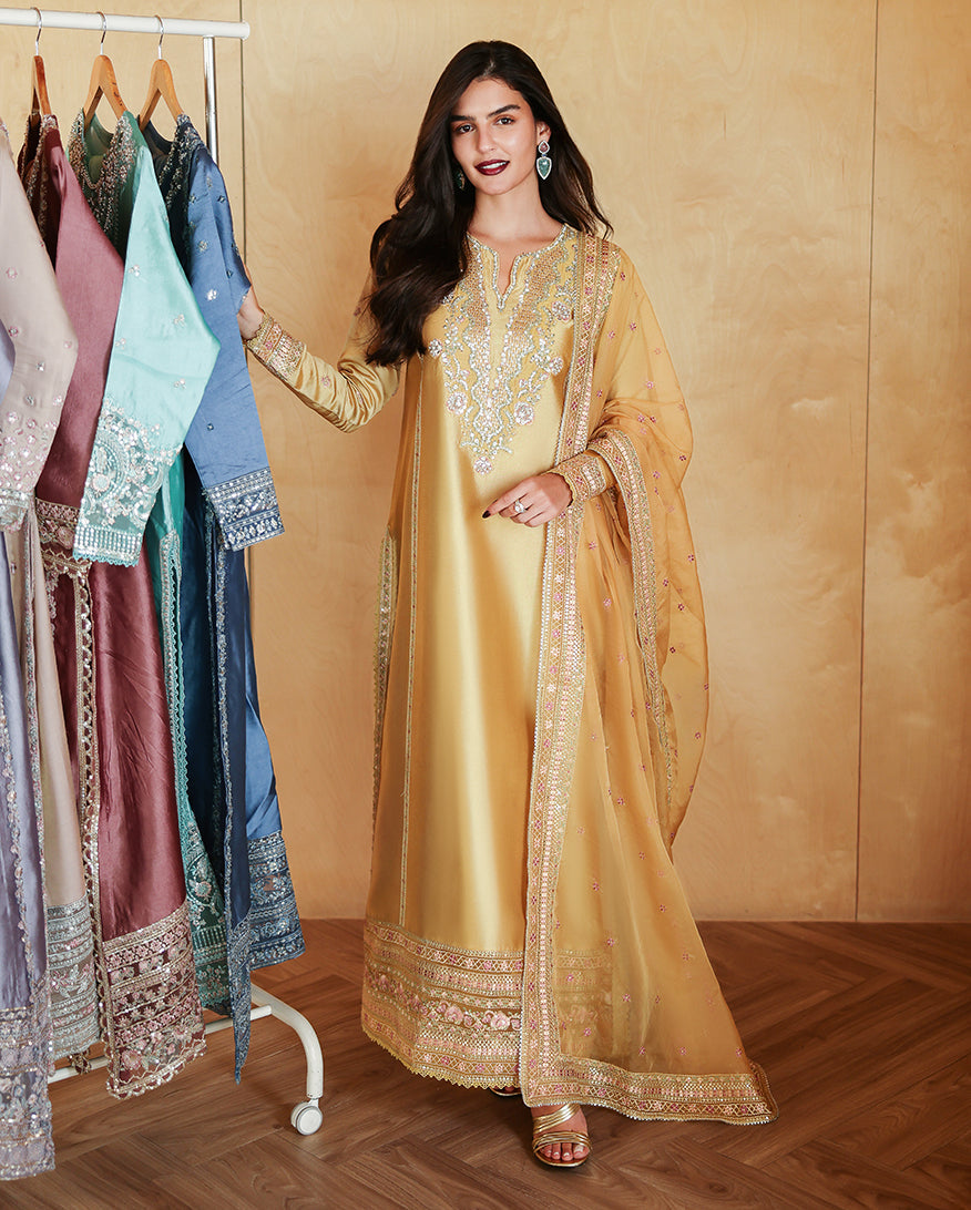 Woman wearing a golden yellow luxury pret suit with silver embroidery, Zarminay collection