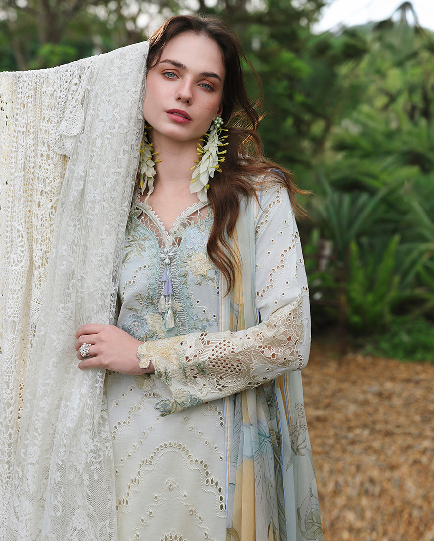 Woman wearing lemon yellow embroidered lawn unstitched suit with lace dupatta and floral earrings, Secret Garden collection