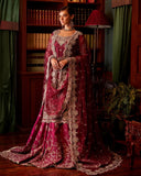 Woman wearing magenta embellished Net bridal lehenga with sheer dupatta draped over the arm