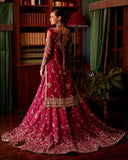 Back view of woman wearing magenta embellished Net bridal lehenga with sheer dupatta train
