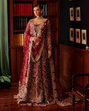 Woman wearing red embellished Net bridal gown with sheer dupatta draped over the arm