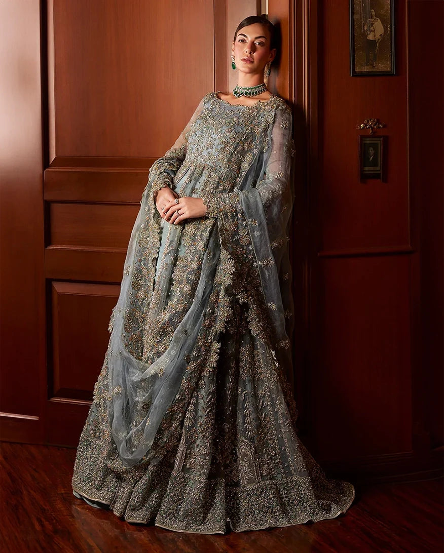 Woman wearing teal blue embellished Net bridal gown with dupatta draped over the arm