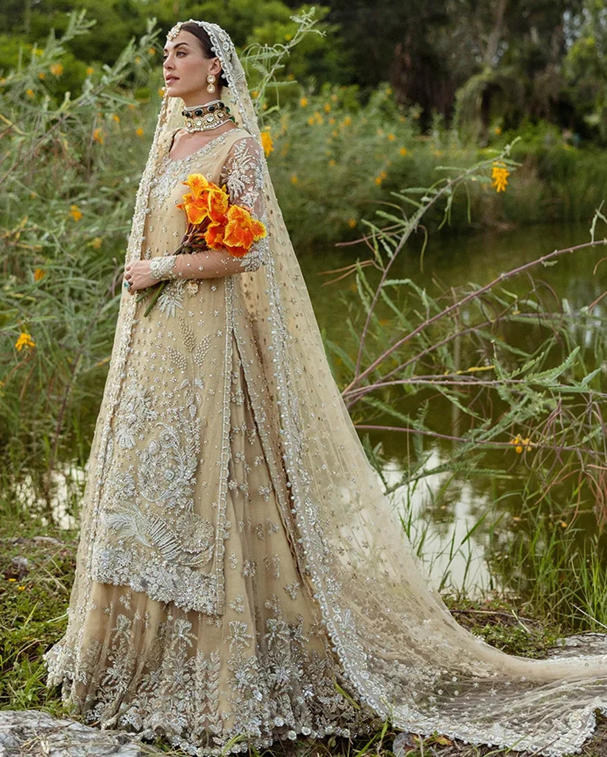 Woman wearing beige embellished Net bridal lehenga with sheer dupatta draped over head