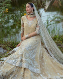 Woman wearing beige embellished Net bridal lehenga, seated with veil draped over shoulder