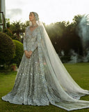 Woman in an Ice Blue Net bridal dress, embroidered dupatta trailing on grass, a Pakistani bridal wear design
