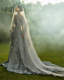 Woman in an Ice Blue Net bridal dress with trailing veil, a Pakistani bridal dress in misty garden setting