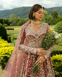 Woman wearing a Tea Pink Net bridal dress holding a bouquet, one of Mushq's pakistani designer bridal dresses