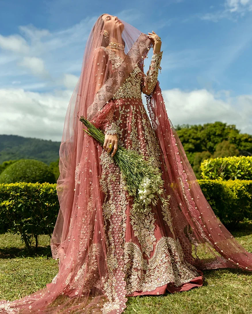 Woman in a Tea Pink Net walima bridal dress holding a bouquet, veil draped over head