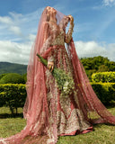 Woman in a Tea Pink Net walima bridal dress holding a bouquet, veil draped over head
