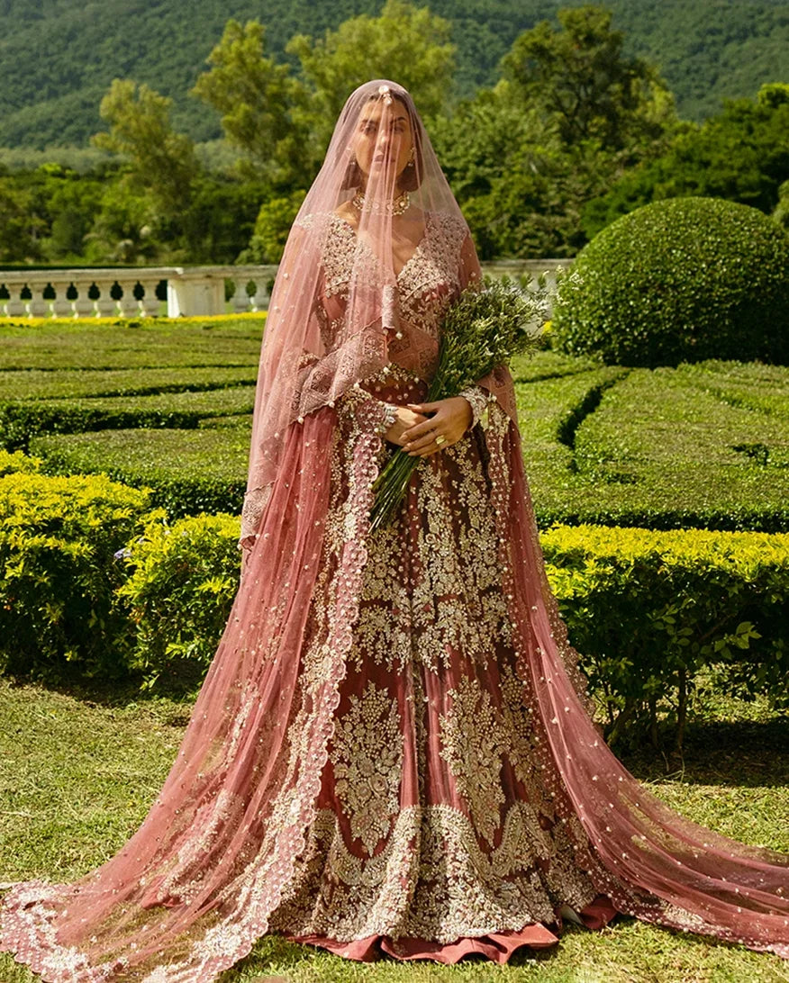 Woman wearing a Tea Pink Net bridal dress and veil, one of Mushq's pakistani wedding dresses