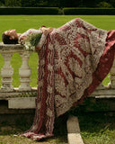 Woman reclining in a Tea Pink Net bridal dress with dense embroidery, one of Mushq's pakistani bridal dresses