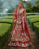 Woman wearing blood red embellished Net bridal lehenga with sheer dupatta draped over head