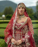 Close-up of woman wearing blood red embellished Net bridal lehenga with maang tikka jewelry