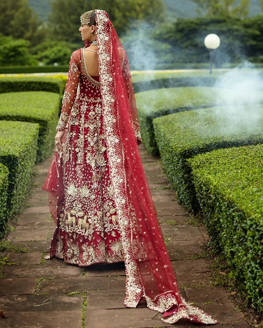 Back view of woman wearing blood red embellished Net bridal lehenga with sheer veil