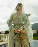 Close-up of woman wearing aqua green embellished Net bridal lehenga with sheer veil and jewelry