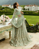 Woman wearing aqua green embellished Net bridal lehenga with dupatta draped over the arm