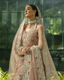 Woman wearing peach embellished Net bridal lehenga with sheer dupatta draped over head