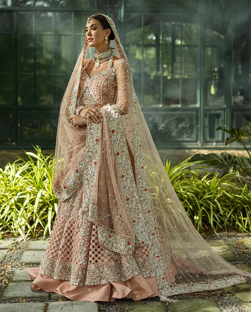Woman wearing peach embellished Net bridal lehenga with sheer dupatta, front view