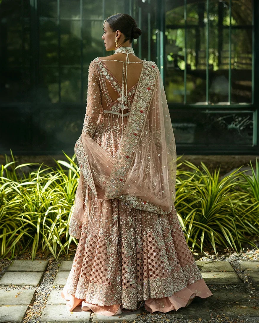 Back view of woman wearing peach embellished Net bridal lehenga with open back detailing