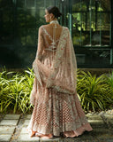 Back view of woman wearing peach embellished Net bridal lehenga with open back detailing